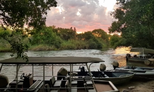P3 tender boats on the beach of the river bank with the sun going down in the background